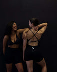 Witness the power and grace of two women as they rock their workout attire - black sports bras and shorts, including trendy open back sports bras.