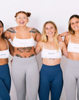 Four fit women in sports bras and leggings strike a pose, radiating confidence and strength. A snapshot of empowerment and athleticism.