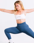 Stay stylish during workouts with this woman in blue leggings and a white sports bra.