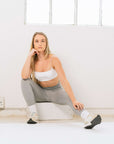 A woman wearing grey leggings and white sports bras, ready to conquer her workout in style.