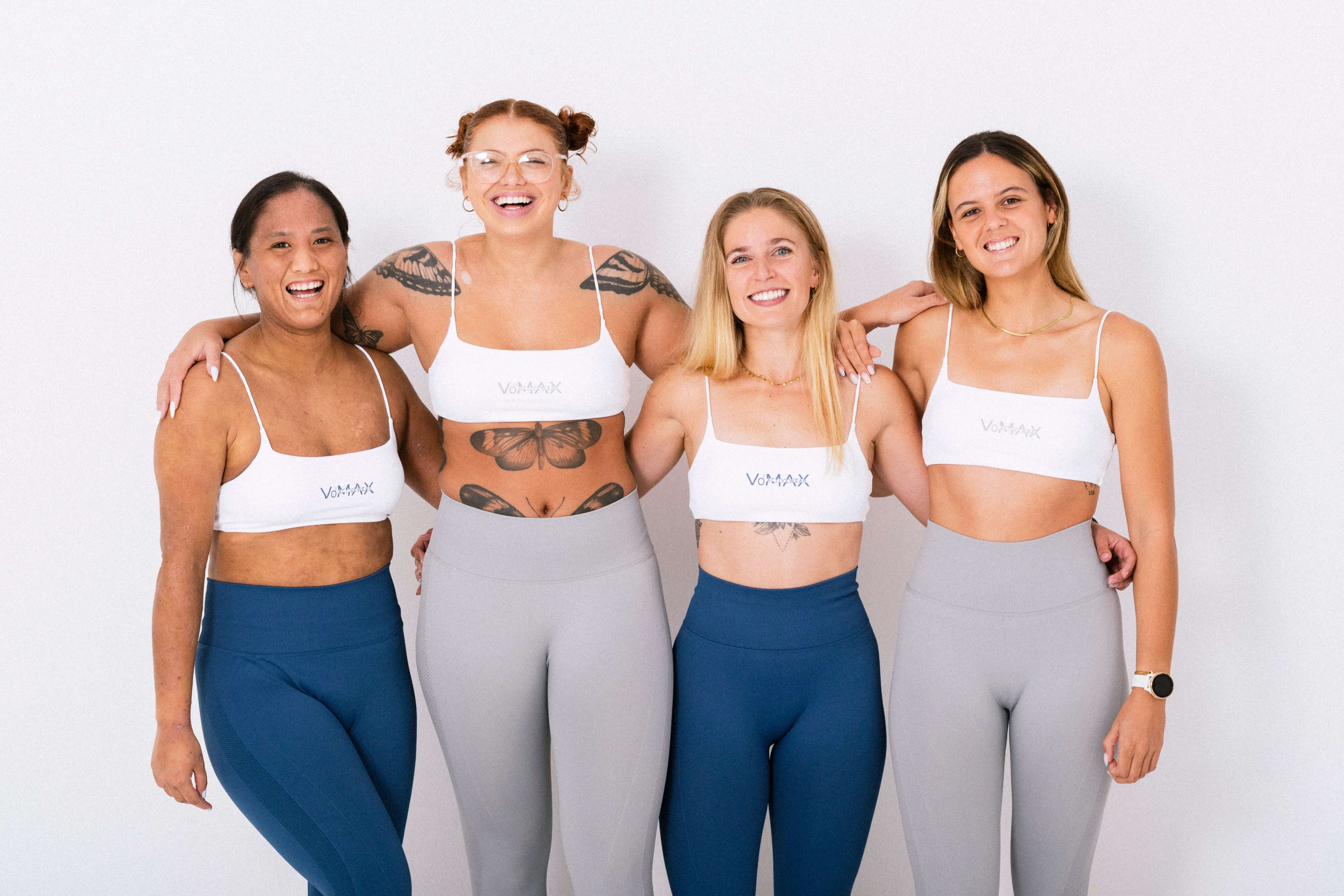 Four fit women in sports bras and leggings strike a pose, radiating confidence and strength. A snapshot of empowerment and athleticism.