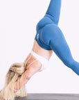 Stay stylish during workouts with this woman in blue leggings and a white sports bra.