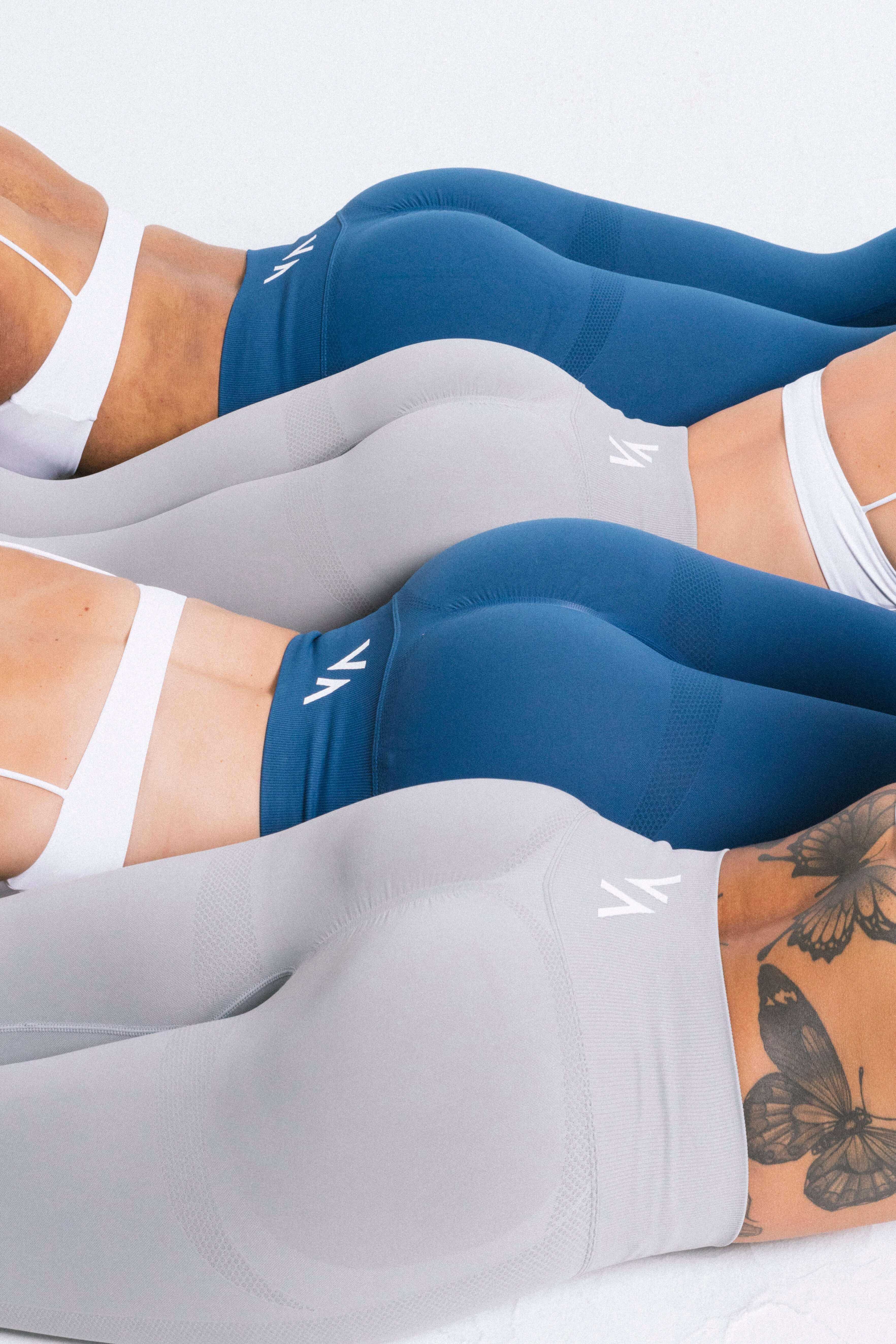 Group of women in blue and gray leggings laying down, dressed in female activewear.