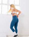 Effortlessly fashionable, the woman in blue leggings and a white sports bra top is a vision of sophistication.